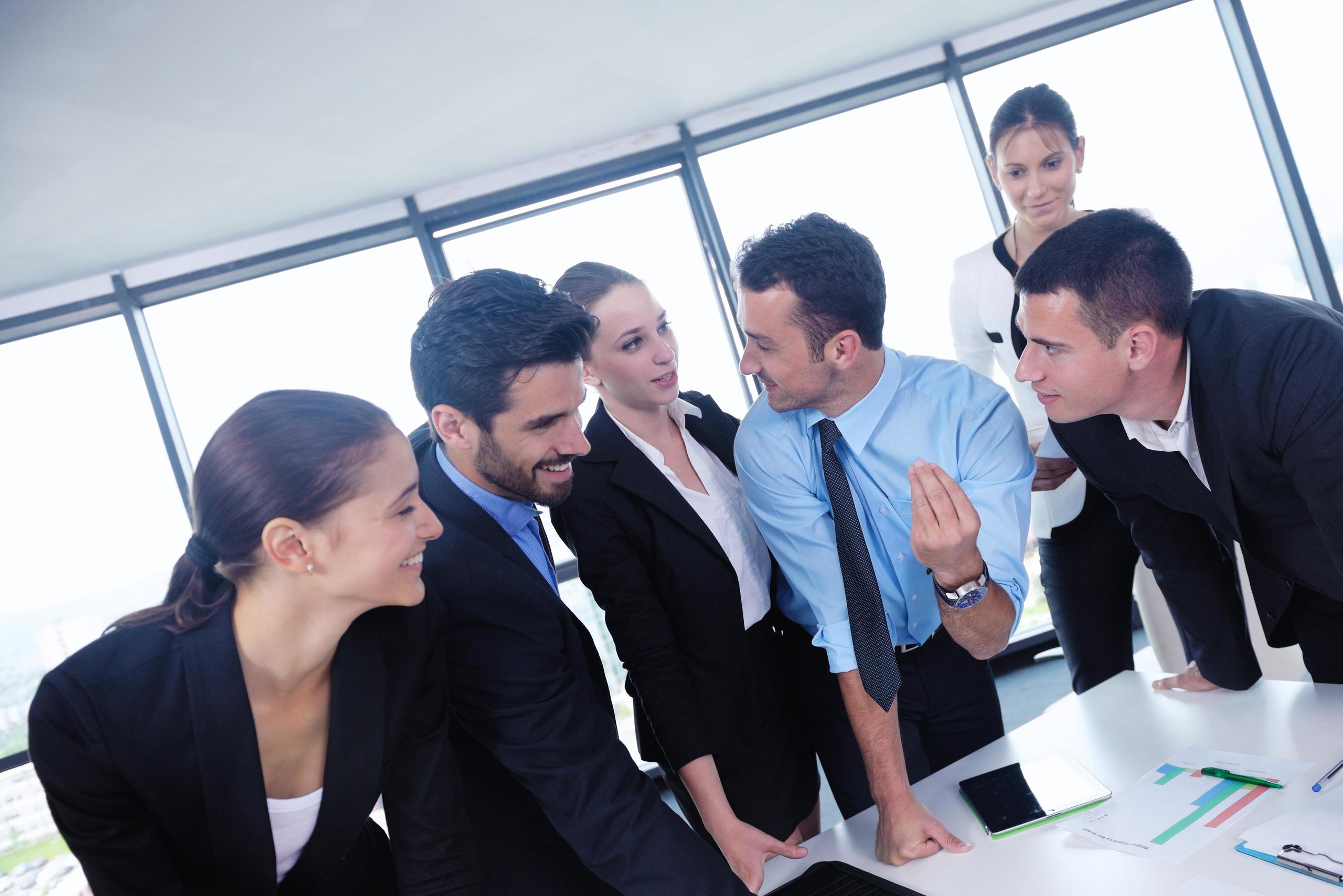 A group of diverse business professionals gathered around a conference table engaged in discussion