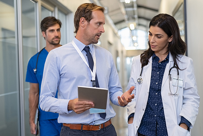 A doctor and two nurses engage in conversation in a hospital hallway, discussing patient care and medical procedures